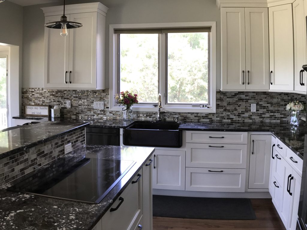 White kitchen with dark farmhouse sink, glass tile backsplash